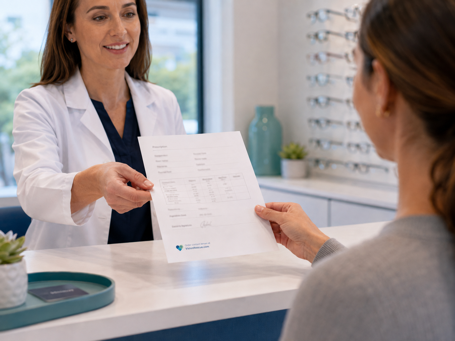 An optometrist hands a contact lens prescription to a patient at the practice counter